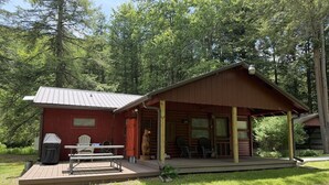 A cabin with a porch, a covered table, and chairs.