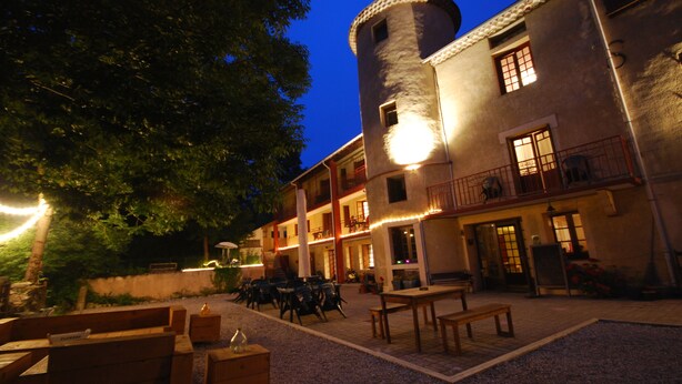 Ein Innenhof mit Außenbestuhlung, einem Turm und einem Gebäude mit mehreren Balkonen und Fenstern.