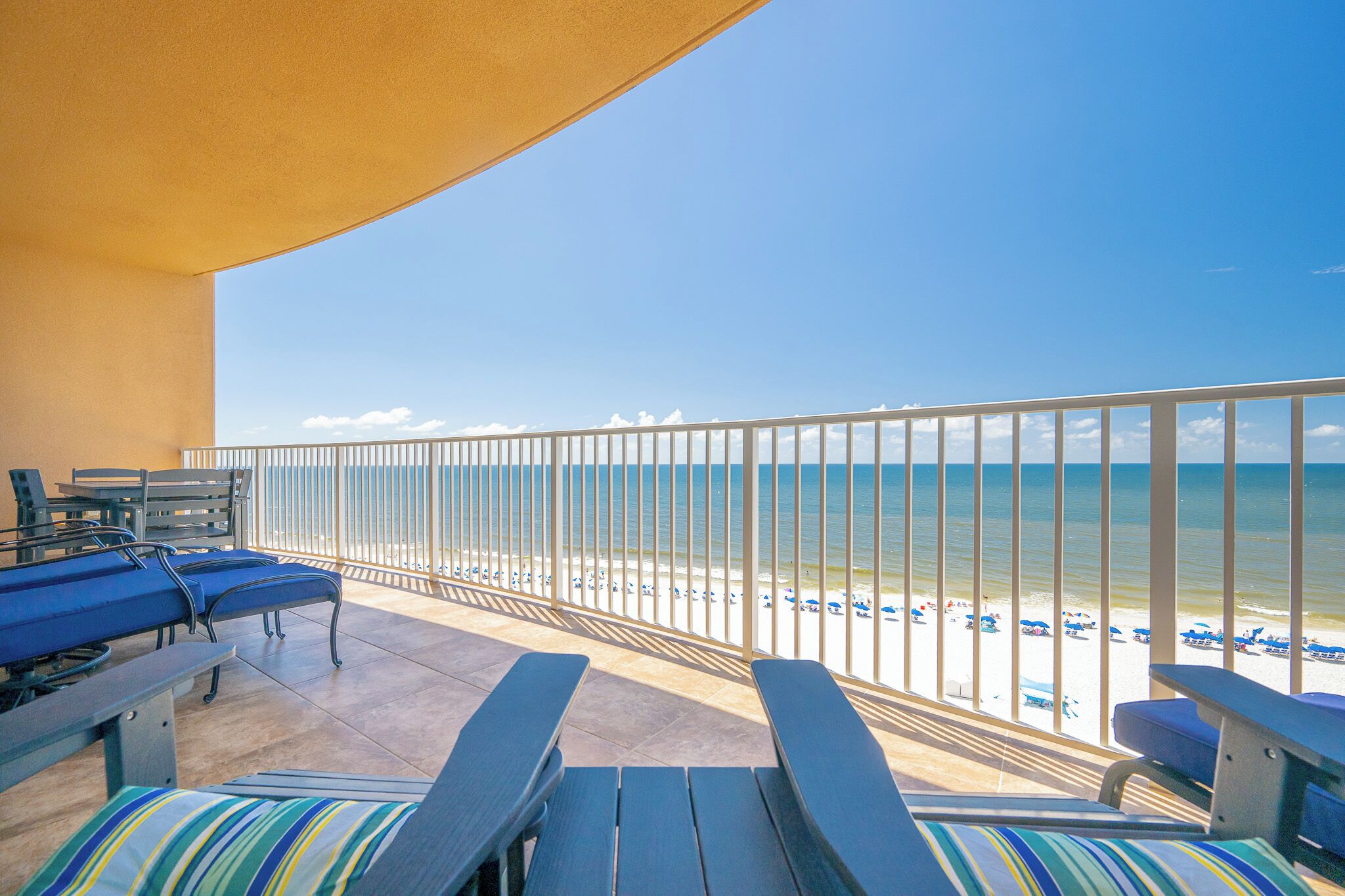 Un balcon avec vue sur la plage, équipé de chaises longues et d’une table.