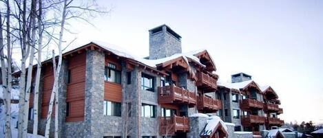 A multi-story lodge with stone and wood exterior, balconies, and snow-covered surroundings.