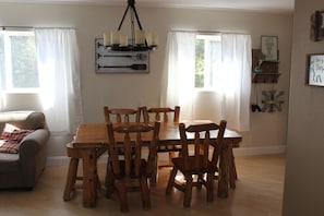 Relax in this inviting dining area with a wooden table and six chairs, surrounded by decorative items and a plush sofa.