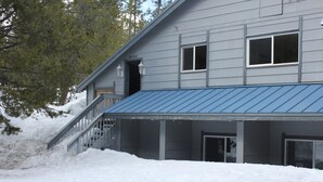 A two-story house with a blue roof, a covered porch, and a staircase leading to the entrance. - Spacious Mountain Retreat, great for groups & families (Arnold)