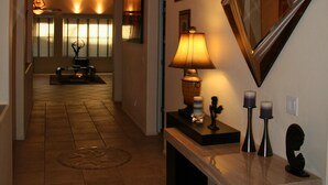 Un couloir avec un banc, des lampes fixées au mur et un miroir.