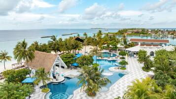 Un resort con una piscina grande, palmeras y vista al océano.