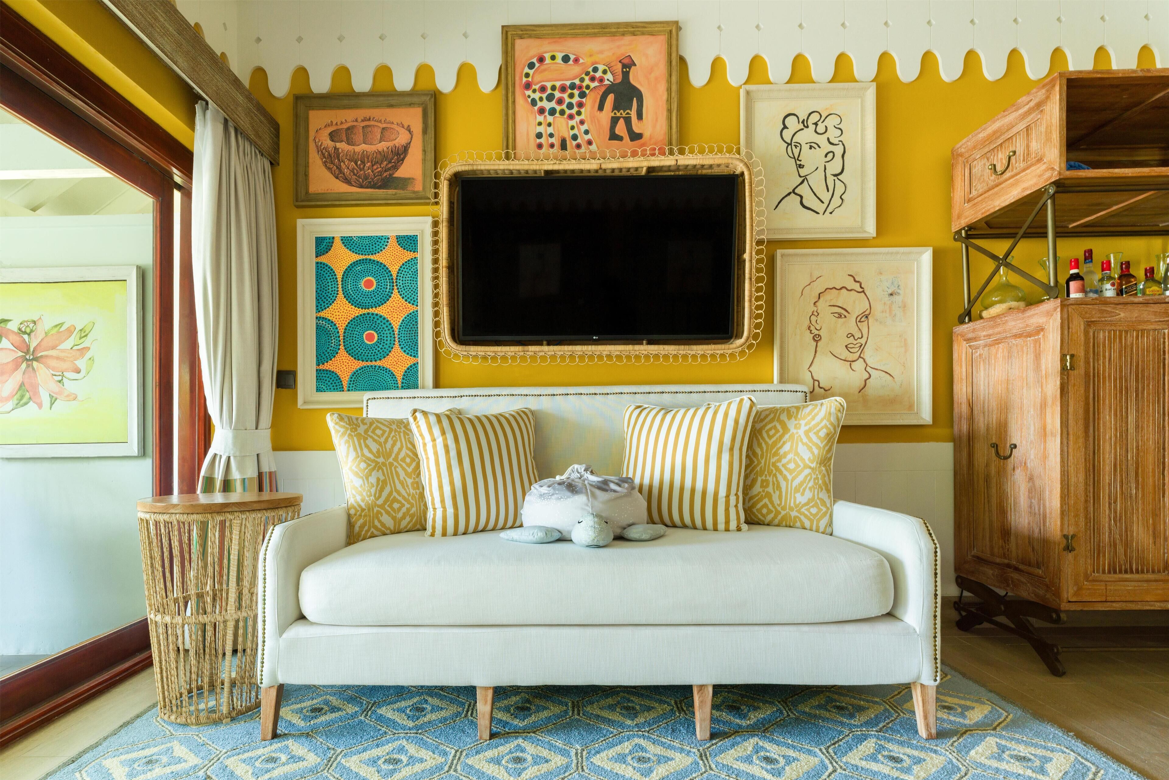 A cozy living room with a sofa, patterned cushions, and a decorative wall with artwork.