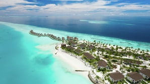 An aerial view of a resort with overwater bungalows, a beach, and clear turquoise waters. - SAii Lagoon Maldives, Curio Collection by Hilton (Eh'mafushi)