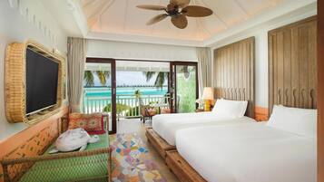 A hotel room with a bed, a chair, a TV, and a balcony with a view of the ocean.