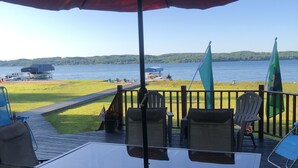 An outdoor patio with a table and chairs, overlooking a lake with boats and a dock. - Terrific Family Getaway on Lake Charleviox with Stunning Views  (East Jordan)