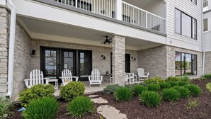 A two-story house with a covered porch, stone facade, and white railings.