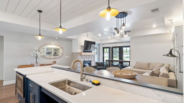 A modern kitchen with a large island, pendant lighting, and a view to the living area.