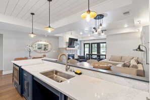 A modern kitchen with a large island, pendant lighting, and a view to the living area. - Downtown Sister Bay Waterfront Condo – Walk to Everything (Sister Bay)