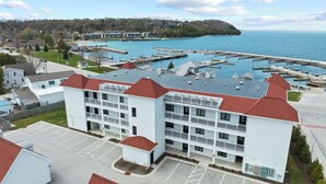 A multi-story hotel with a parking lot and a marina in the background.