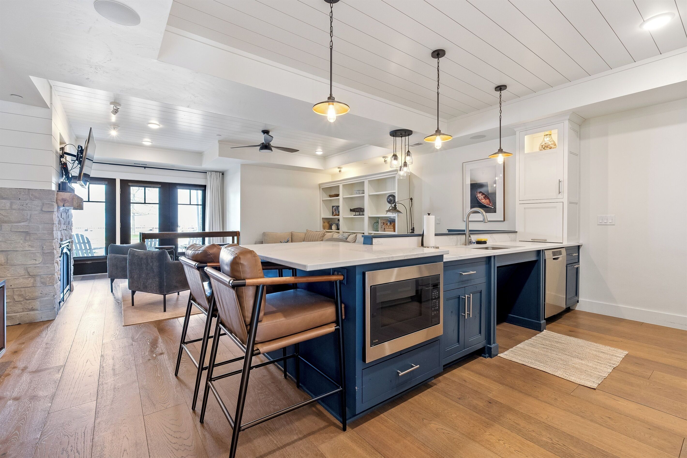 A modern kitchen with a central island, bar stools, and pendant lighting.
