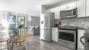 A modern kitchen with stainless steel appliances, white cabinetry, and a marble backsplash. - Beach & Tennis Getaway 3206 (Bonita Springs)