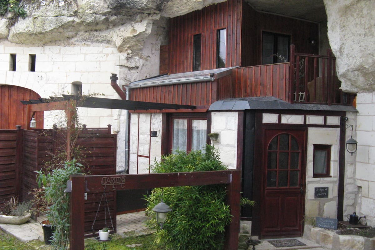 Un edificio rústico de piedra con un nivel superior de madera, una puerta de madera con la leyenda 