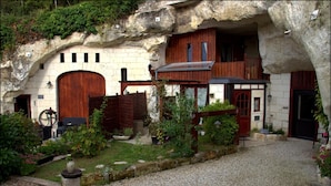 Un edificio rústico de piedra con puertas de madera y un camino de grava.