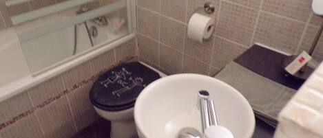 Un baño con inodoro, lavamanos y zona de ducha.