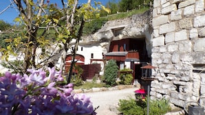 Un edificio de piedra con fachada rústica, un pequeño jardín con flores y una valla de madera.