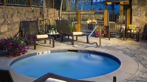 A swimming pool with lounge chairs and a stone wall. - Condo with Gas Fireplace and Spacious Rooms (Cordillera)