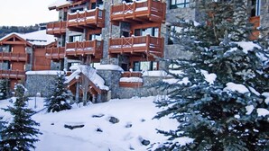 A multi-story lodge with wooden balconies and stone walls, surrounded by snow-covered trees. - Condo with Gas Fireplace and Spacious Rooms (Cordillera)