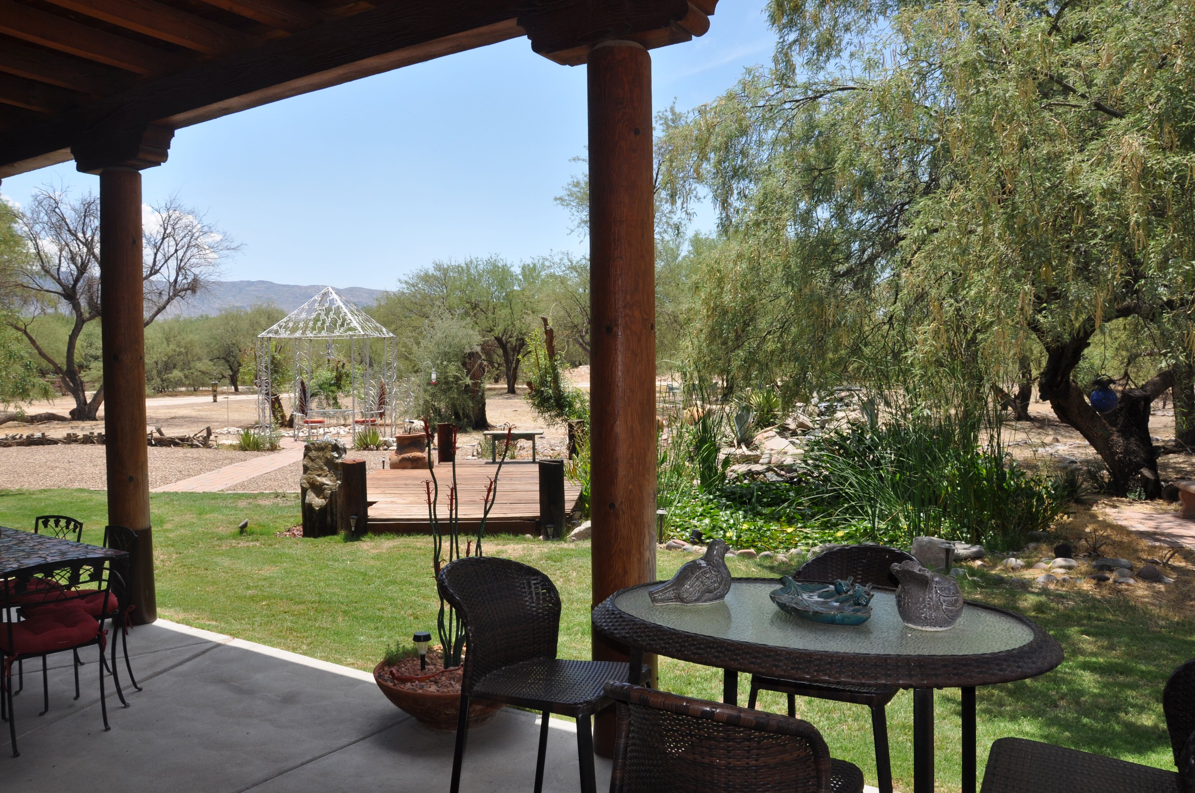 Un patio al aire libre con zona de estar techada, un pabellón y vistas a un paisaje desértico.