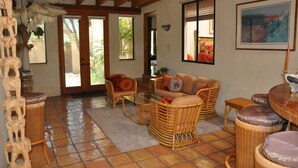 A spacious living area with wicker furniture, a glass coffee table, and a view through a glass door to the outside. - Rancho Privado Tucson AZ (Tucson)