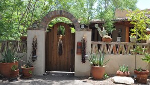 A rustic gate with a wooden door, surrounded by potted plants and a wooden fence. - Rancho Privado Tucson AZ (Tucson)