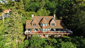 A large, two-story house with a wrap-around porch and a tower-like structure on the roof.