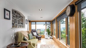 A cozy living room with a green sofa, a wooden coffee table, and a large window offering a view of greenery.