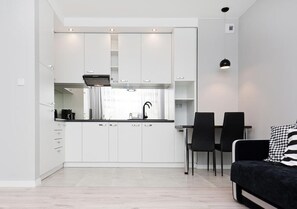 Uma cozinha moderna com armários brancos, bancada preta e um espaço de refeições com duas cadeiras.