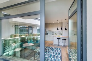 Cozinha moderna com ilha central, iluminação pendente e vista para a varanda externa.