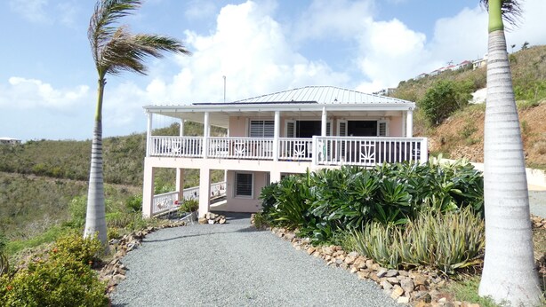 A two-story house with a balcony, surrounded by tropical plants and a gravel driveway. - Ocean View And Breezes, Quiet 1 Bedroom, 1 Bath Private Guest Cottage On 1 Acre (Christiansted)