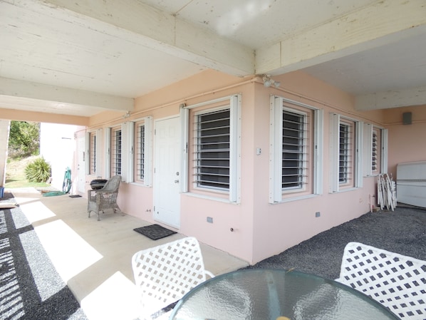 A covered patio area with a glass table, white chairs, and a grill. - Ocean View And Breezes, Quiet 1 Bedroom, 1 Bath Private Guest Cottage On 1 Acre (Christiansted)