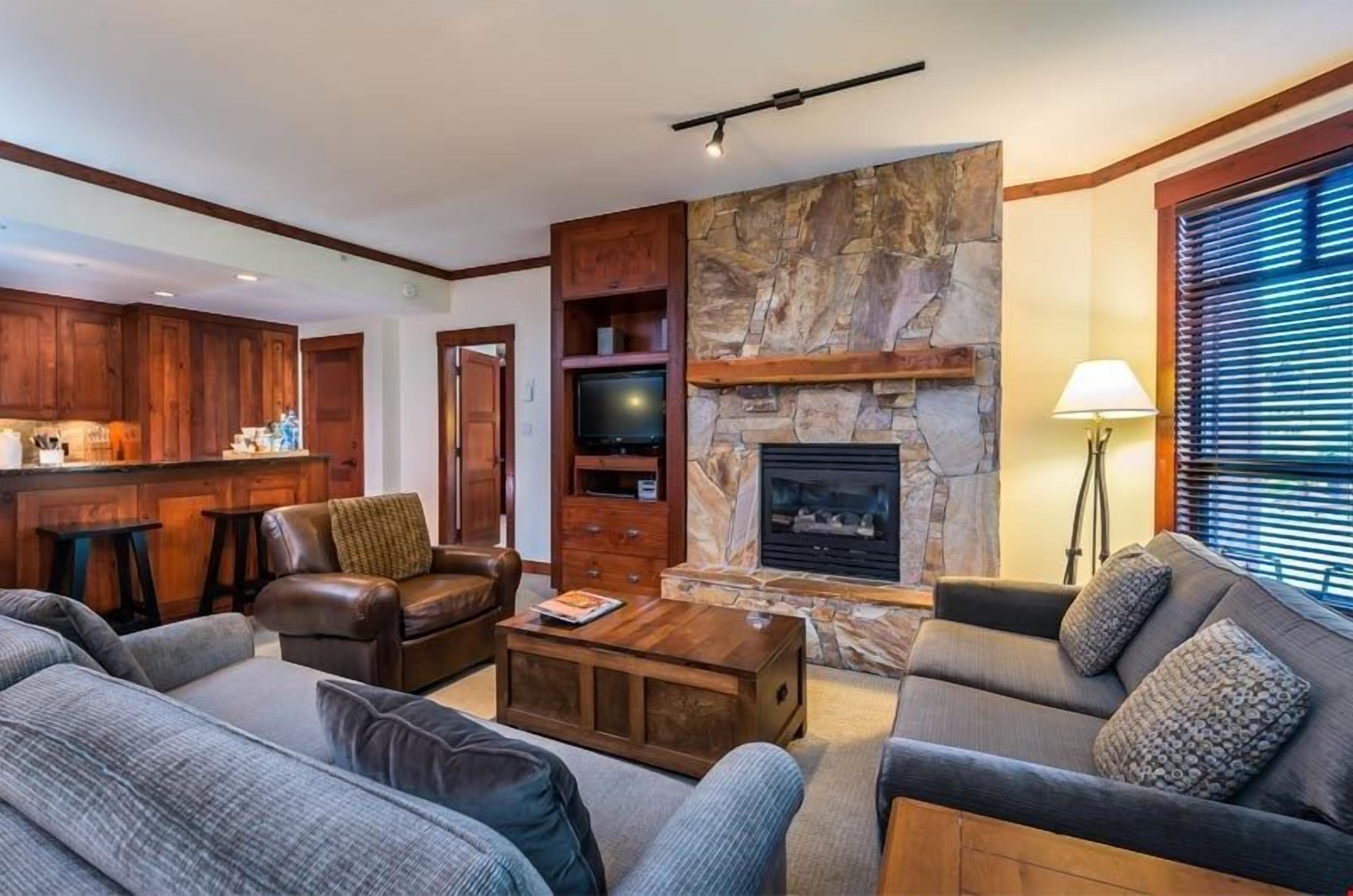 A living room with a stone fireplace, leather sofas, a coffee table, and wooden cabinets.