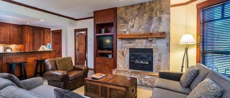 A living room with a stone fireplace, leather sofas, a coffee table, and wooden cabinets.