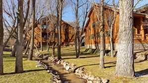 A row of log cabins with a stone-lined stream running through the property.