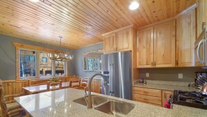 A kitchen with wooden cabinets, a stainless steel refrigerator, granite countertops, and a large island with a sink.