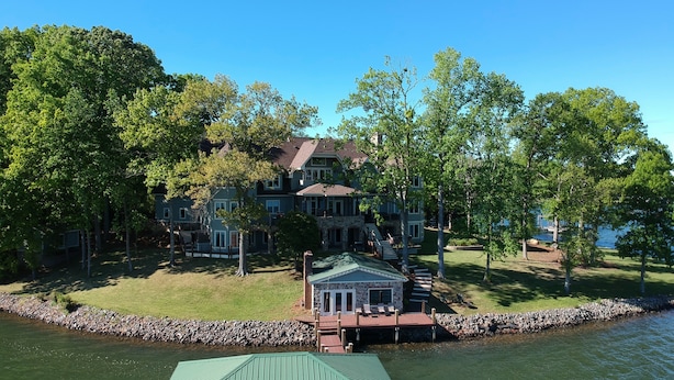 A large house with a dock extending into a lake, surrounded by trees. - Private, Romantic, Lake Norman Waterfront Suite, Hot Tub + Dock + Sunset Views (Mooresville)