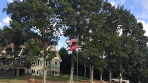 A lakeside property with a flag, trees, and a house. - Private, Romantic, Lake Norman Waterfront Suite, Hot Tub + Dock + Sunset Views (Mooresville)
