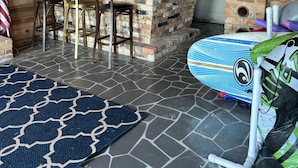 A rustic cabin interior with a stone floor, wooden walls, a bar area, and a kayak. - Private, Romantic, Lake Norman Waterfront Suite, Hot Tub + Dock + Sunset Views (Mooresville)