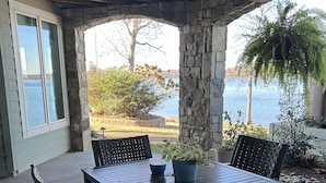 An outdoor patio with a table and chairs, stone pillars, and a view of a lake. - Private, Romantic, Lake Norman Waterfront Suite, Hot Tub + Dock + Sunset Views (Mooresville)