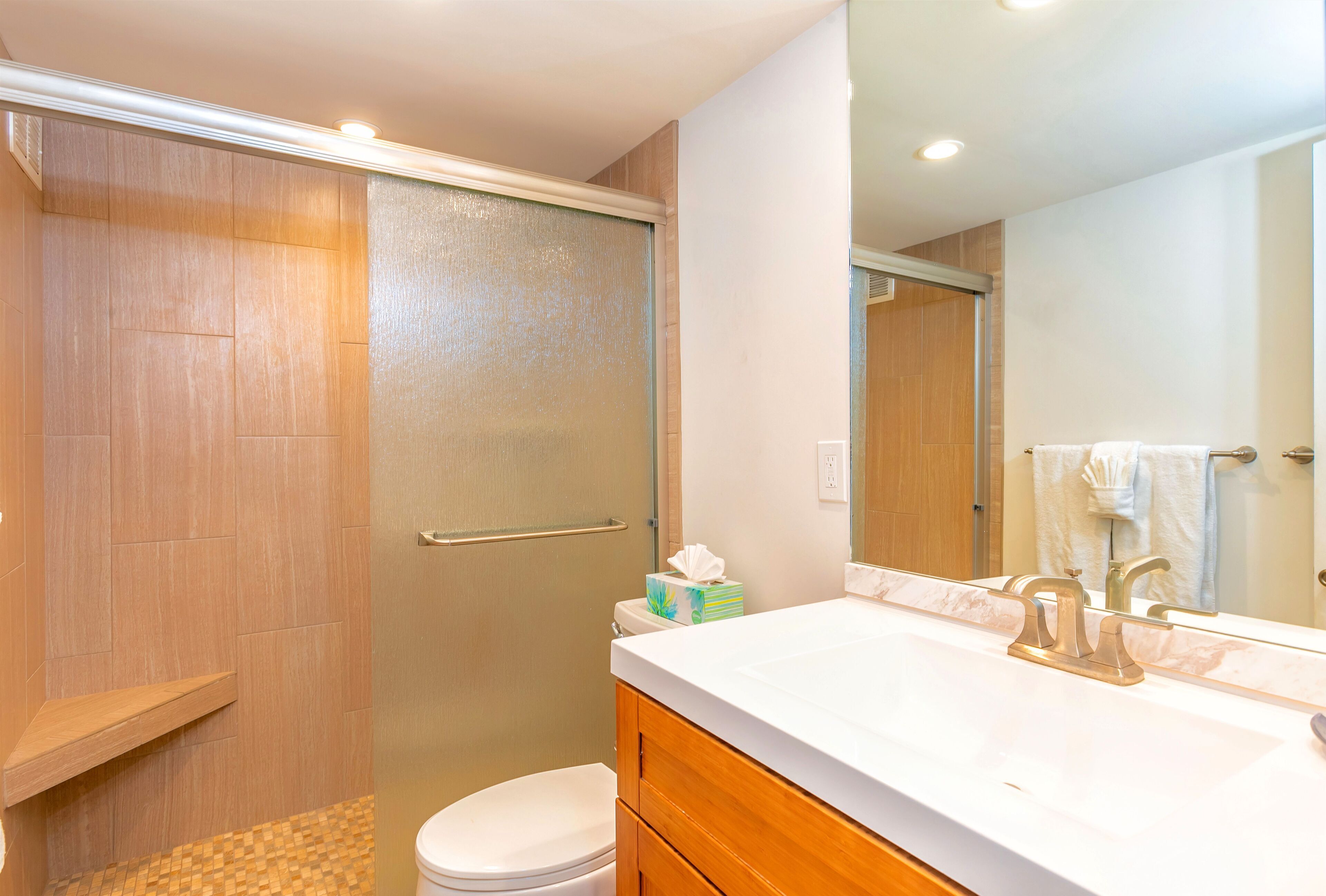 Ein Badezimmer mit Dusche, Toilette, Waschtisch mit Spiegel und Handtuchhalter.