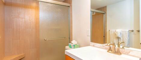 Ein Badezimmer mit Dusche, Toilette, Waschtisch mit Spiegel und Handtuchhalter.