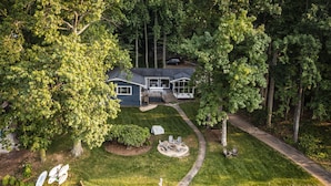 A house with a deck, a fire pit, and a pond.