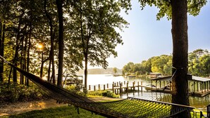 A hammock in a park with a lake and wooden docks.