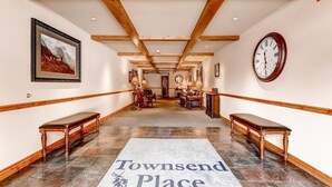 A hallway with a wooden ceiling, benches on either side, a clock on the right, and a rug with "Townsend Place" written on it. - Ski-in Condo | Wood Fireplace, Balcony (Beaver Creek)