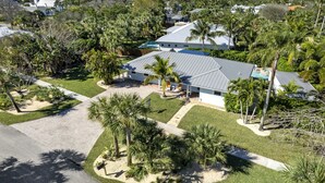 A residential property with a covered patio, palm trees, and a swimming pool. - Well Appointed Home Salt Water Pool & Separate Pool House & Putting Green (Hobe Sound)