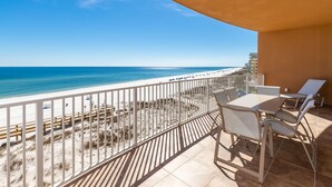 A balcony with a view of the beach, a table with chairs, and a sun lounger. - Low Floor Condo with Pool & Lazy Rive 3 Bedroom Gulf Front - Phoenix Orange Beac (Orange Beach)