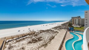 A beach resort with a sandy beach, a wooden boardwalk, a swimming pool, and a view of the ocean and hotel buildings. - Low Floor Condo with Pool & Lazy Rive 3 Bedroom Gulf Front - Phoenix Orange Beac (Orange Beach)