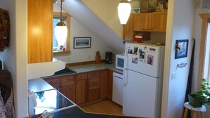 A kitchen with wooden cabinets, a refrigerator, a microwave, and a dining area with a table and chairs.